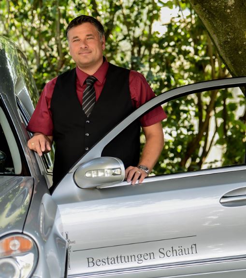 Walter Schäufl neben einem Bestattungsfahrzeug
